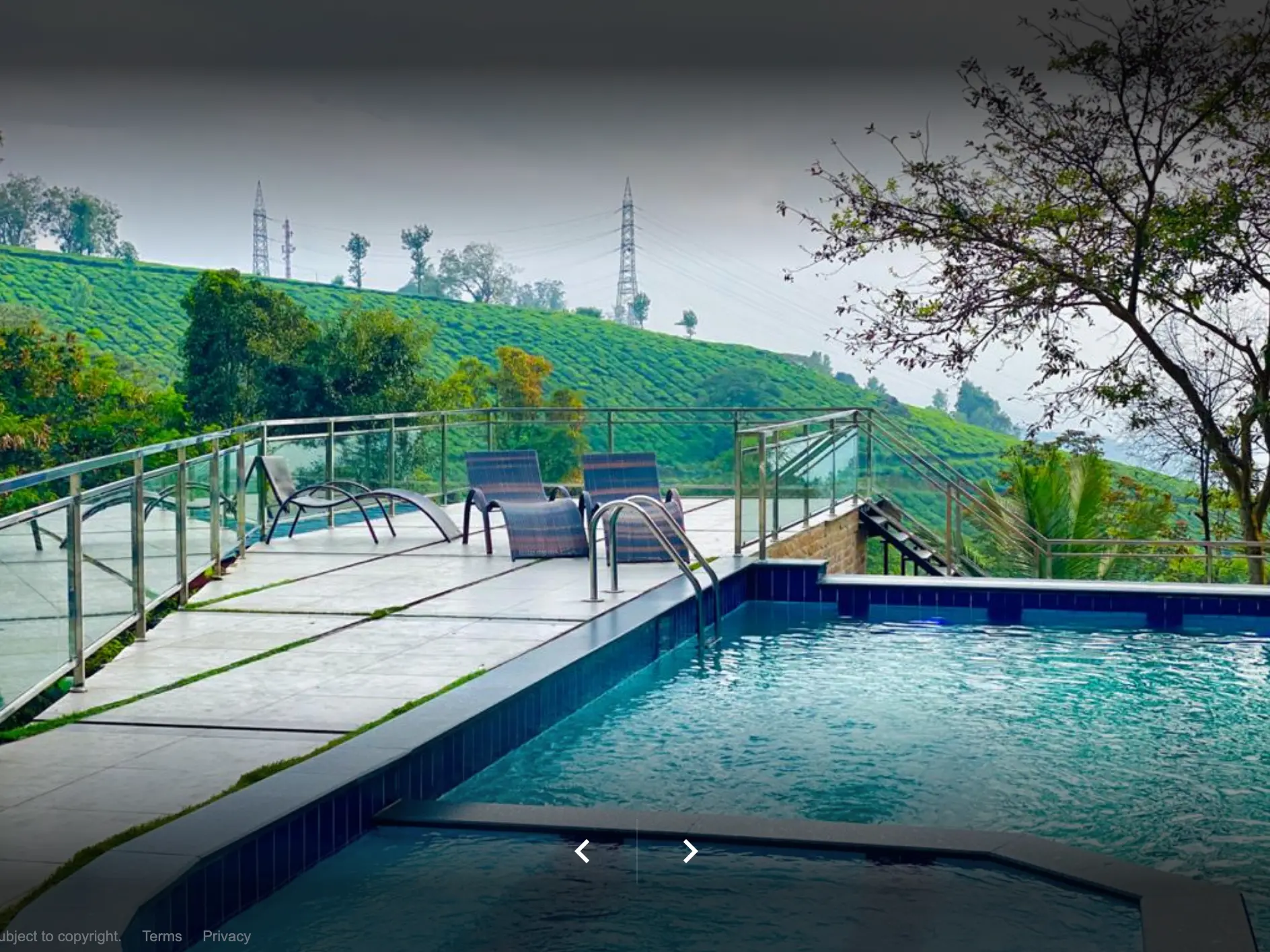 Outdoor swimming pool at Grand Valley Resort, Munnar, with the tea plantation hill rising behind it