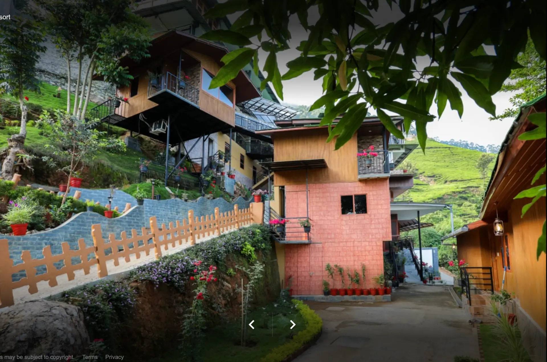 Stone-paved walkway climbing past the wooden hillside cottages and potted flowers at Grand Valley Resort
