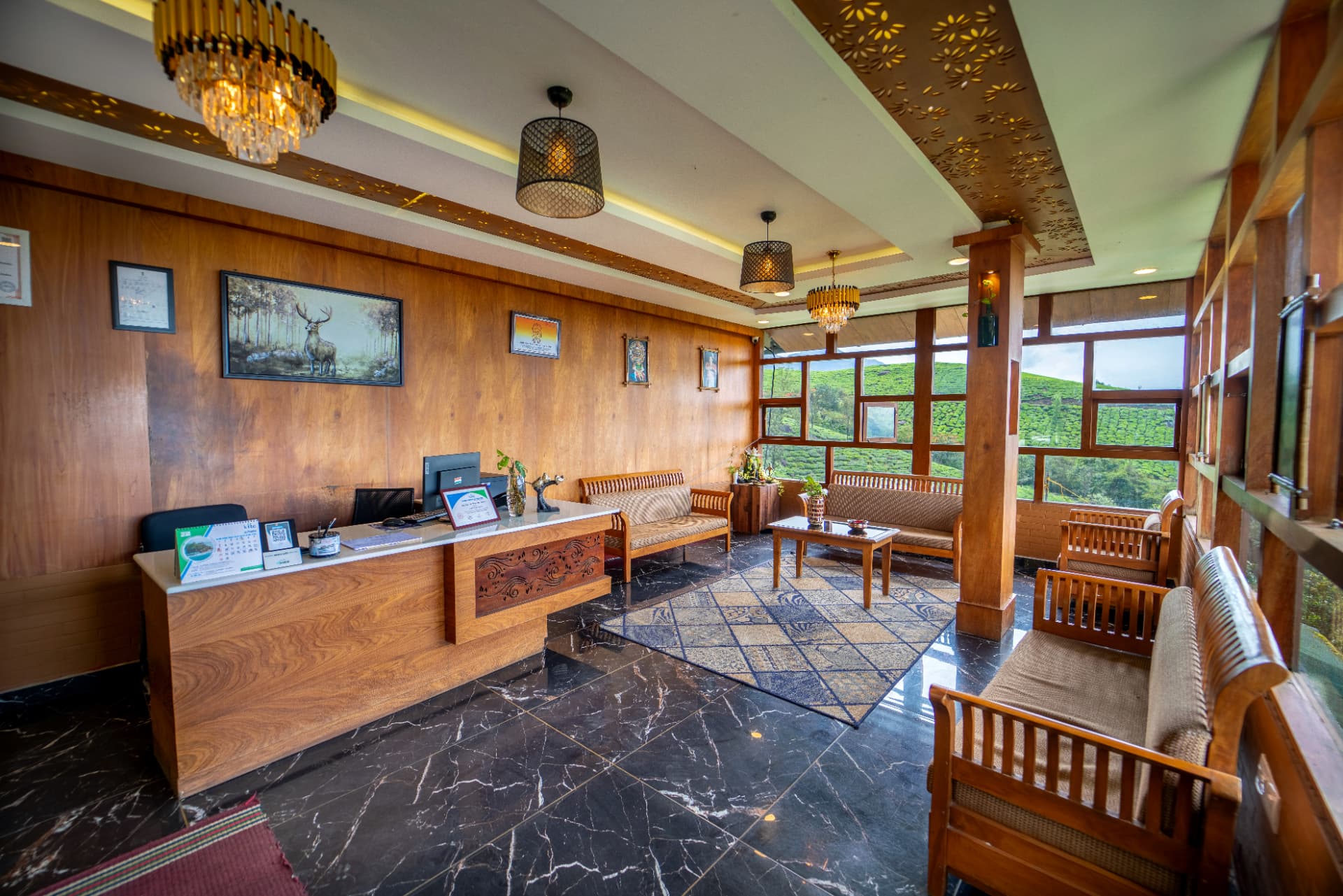 Reception desk at Grand Valley Resort, Munnar, with the tea-garden windows behind it