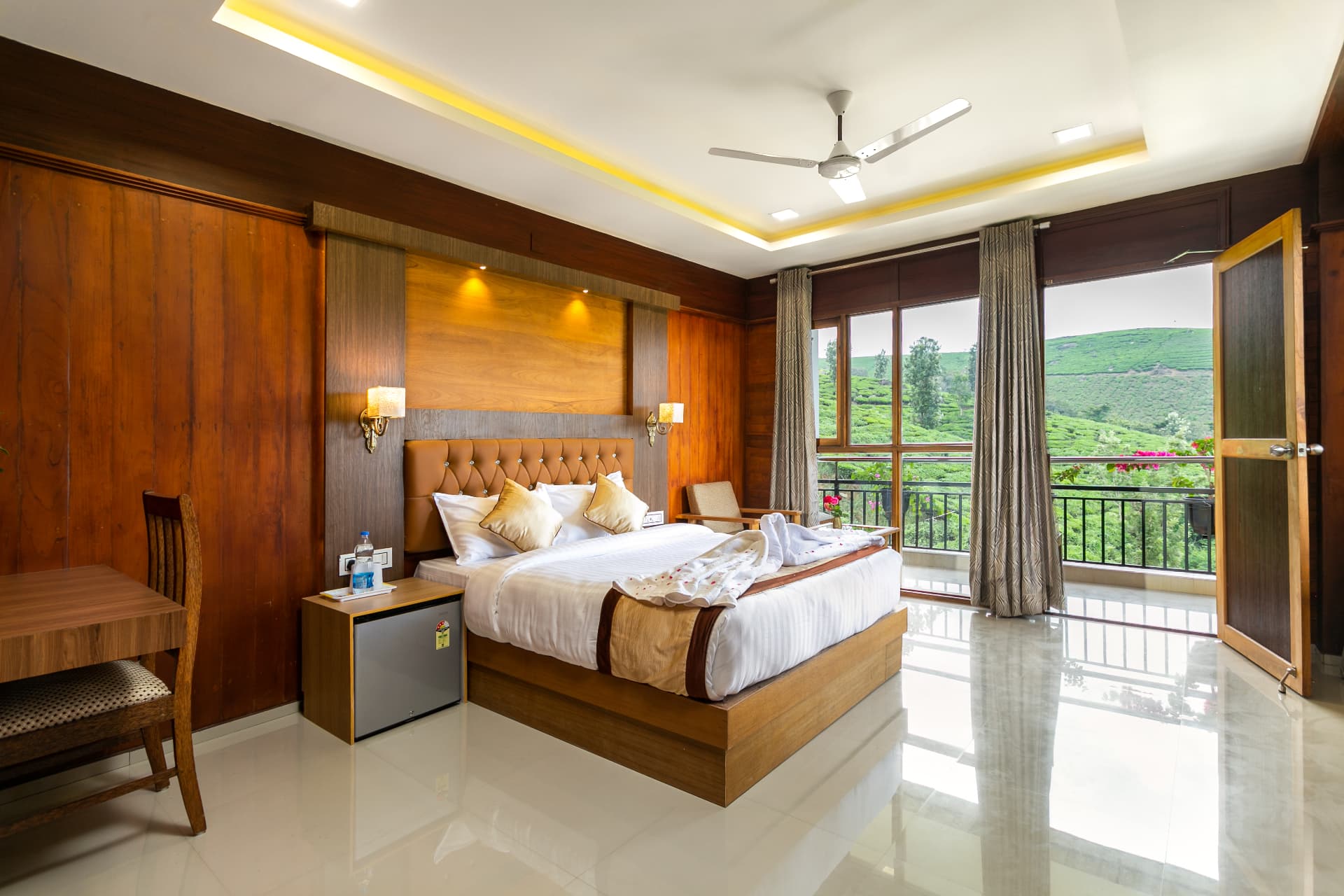 Premium Valley View Room with Balcony at Grand Valley Resort Munnar — king bed, teak panelling and balcony doors open to the tea slopes